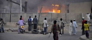 875659_people-watch-as-smoke-rises-from-the-police-headquarters-after-it-was-hit-by-a-blast-in-nigeria-s-northern-city-of-kano