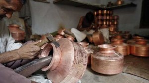 Workers use hammers to form copper pitchers inside a workshop in the western Indian city of Ahmedabad